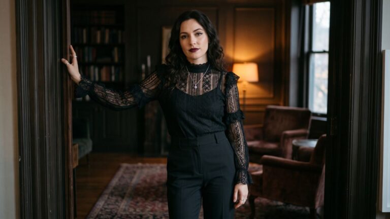 Mujer con blusa negra de encaje, pantalón oscuro y joyería plateada para un look gótico de Halloween